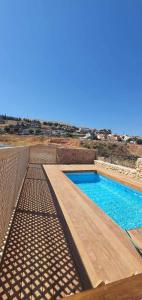 una piscina con terraza de madera y agua azul en צימר בקתה מול הנוף, en Safed