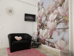 a living room with a black chair and pink flowers at Suite Room Fiumicino in Fiumicino