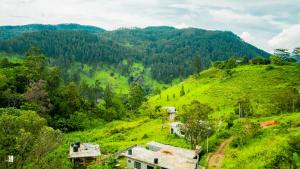 a village on a green hill with trees and mountains at Bougainvillea Resort in Bandarawela