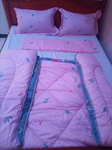 a bed with a pink comforter with butterflies on it at Pearl Motel Buloba in Buloba