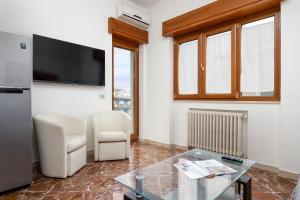 Una sala de estar con televisión, mesa y sillas. en Rossella Holiday Home, en Sorrento