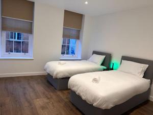 two beds in a room with two windows at Farringdon Apartments in London