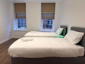 two beds in a room with two windows at Farringdon Apartments in London