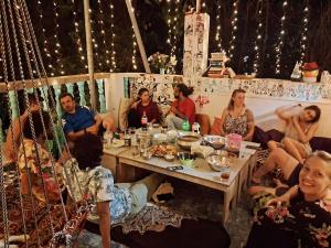 een groep mensen die rond een tafel zitten te eten bij Dreamcatcher House & Hostel at Arambol Beach in Arambol