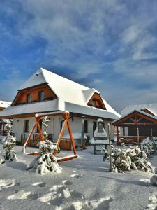 Una casa en la nieve con un columpio en Vila Svistovka, en Stará Lesná