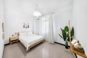 a white bedroom with a bed and a potted plant at XICHI Homestay in Jinning