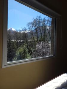 a window in a bedroom with a view of trees at Baguales Alojamientos Patagonicos in Villa La Angostura
