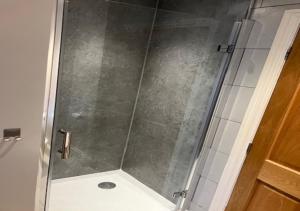 a shower with a glass door in a bathroom at Inglenook Cottage in Wandylaw