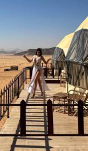 瓦迪拉姆的住宿－Wadi Rum Mars Camp，沙漠木板路上穿白色衣服的女人