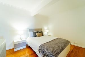 a white bedroom with a bed and two lamps at Ana's Place in Funchal
