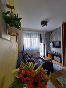 - un salon avec un canapé et une table fleurie dans l'établissement Apartman Rajska dolina Titova vila, à Palisat