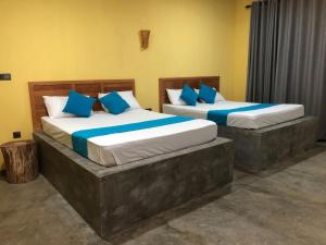 Palabaddala Tea and Eco Lodge في راتنابورا: سريرين مع وسائد زرقاء في الغرفة