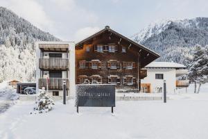 a sign in the snow in front of a building at Tante Anna Apartments in Sankt Gallenkirch