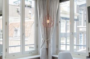 Cette chambre dispose de grandes fenêtres et d'une lampe. dans l'établissement Jordaan Suite bed and bubbles, à Amsterdam