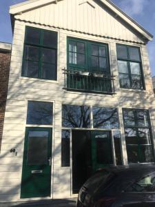a white house with green windows and a balcony at Bed and Breakfast du Parc in Zaandam