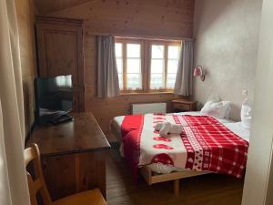 een slaapkamer met een bed, een bureau en een televisie bij L'Auberge de L'Ours in Vers L'Eglise