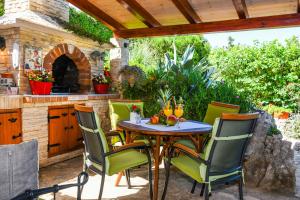 a table and chairs on a patio with an outdoor oven at Holiday Home Paradise Beach in Šibenik