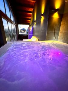 una piscina de agua púrpura en una habitación con ventanas en La Siègià Resort spa, en Massa Marittima