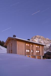 a building in the snow with a mountain in the background at Ciasa Plandros Apartments in La Valle