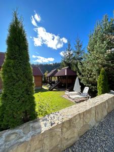 a garden with a stone retaining wall and a tree at Guest House Kaspiy in Bukovel