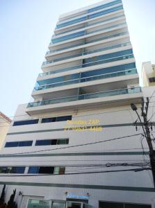 un edificio alto con un cartel en el costado en Apt Matheus Almeida - Anfitriões Gildo e Renata Localização privilegiada, conforto e seu amplo espaço são os seus diferenciais, en Guarapari