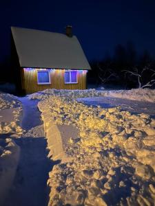 a building with lights in the snow at night at Brīvdienu namiņš in Ludza