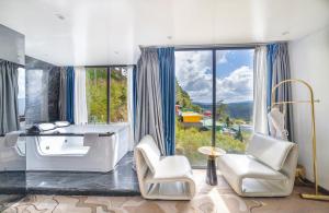 a bathroom with a tub and chairs and a large window at New Century Dalat Hotel in Da Lat