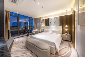 a bedroom with a large white bed and a large window at New Century Dalat Hotel in Da Lat