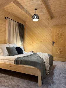 ein Schlafzimmer mit einem großen Bett in einem Holzzimmer in der Unterkunft Domki WIDOKÓWKA in Bukowina Tatrzańska