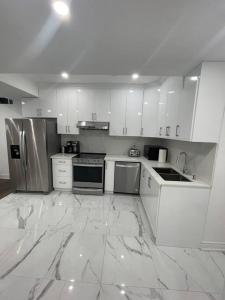 een grote witte keuken met witte kasten en apparaten bij luxury & Spacious 2 bedrooms serviced apartment in Brampton