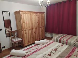 - une chambre avec 2 lits et un rideau rouge dans l'établissement Maison Vallet CIR VDA-VALTOURNENCHE n 0023, à Valtournenche