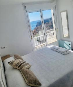sypialnia z łóżkiem z poduszkami i dużym oknem w obiekcie Luz de Mar w mieście Almería