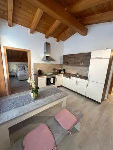 una cocina con armarios blancos y sillas rosas en LEO Apart 2 en Radfeld