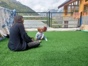 una mujer y un bebé sentados en la hierba en Amma Home Stay Keylong en Kyelang