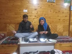 Ein Mann und eine Frau sitzen auf einer Bank in einem Zimmer in der Unterkunft Amma Home Stay Keylong in Kyelang