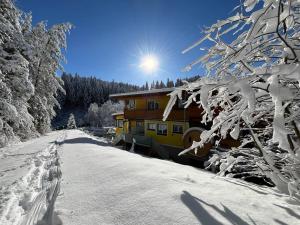 ein schneebedecktes Haus neben einer schneebedeckten Straße in der Unterkunft Gasthof Klug zum Ehrensepp in Modriach