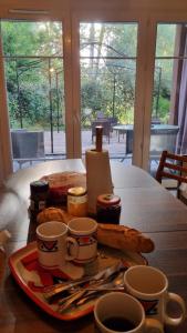 einen Tisch mit einem Teller Essen und Tassen Kaffee in der Unterkunft Sur le bassin d'Arcachon in Lanton
