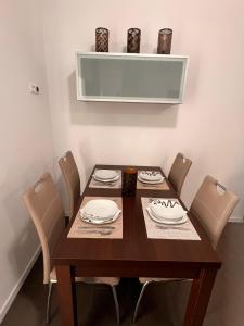 a dining room table with chairs and a wooden table with plates at Stella Apartment in Lamač