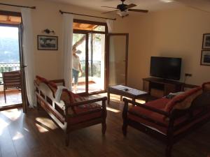 a living room with two chairs and a flat screen tv at Magda's Hotel Apartments in Parga