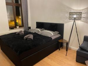 - un lit noir dans une chambre avec une lampe dans l'établissement Leipzig City Apartment - Südperle - direkt im Geschehen, à Leipzig
