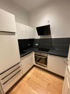 La cuisine est équipée de placards blancs et d'un four avec plaques de cuisson. dans l'établissement Leipzig City Apartment - Südperle - direkt im Geschehen, à Leipzig