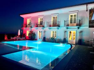 a swimming pool in front of a house at night at Villa Nonna Cicci Boutique Hotel - SPA in Cisterna dʼAsti