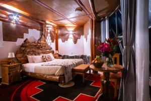 1 dormitorio con 1 cama y 1 mesa con flores en StarDomeLodge, en Ollantaytambo