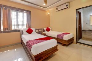 a room with two beds and a bathroom with a shower at Bhagirathi Residency in Anantapur