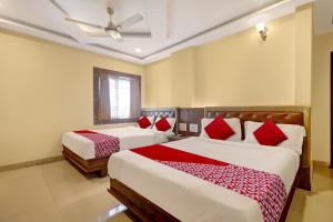 a bedroom with two beds with red pillows at Bhagirathi Residency in Anantapur