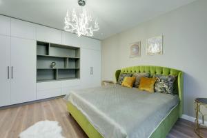 sypialnia z zielonym łóżkiem i żyrandolem w obiekcie Central Luxury Apartments w mieście Jełgawa