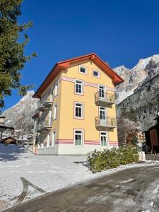 um edifício amarelo com um telhado vermelho nas montanhas em Appartamento Vale e Schena Cortina D'Ampezzo em San Vito di Cadore