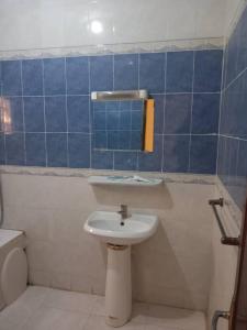 a bathroom with a sink and a toilet and blue tiles at Chambre Chez Jean in Nouakchott