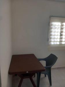 a wooden table and a chair in a room with a window at Chambre Chez Jean in Nouakchott