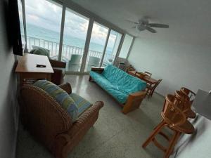 San Juan 1 BR Ocean Front Condo in Condado '8' في سان خوان: غرفة معيشة مع أريكة وكراسي والمحيط